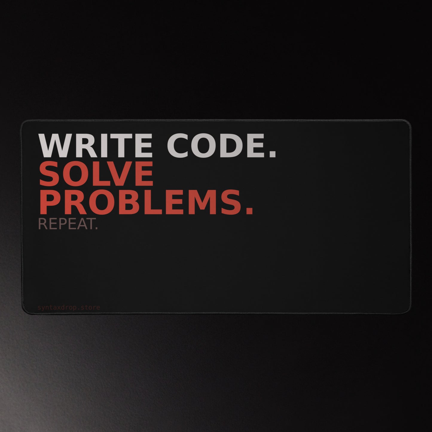 Software developer desk mat on black background with off-white and red typography reading Write Code Solve Problems Repeat